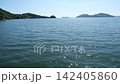 A panoramic view overlooking a calm sea and islands sparkling with light. 142405860