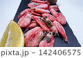 Pink shrimps with lemon slices and spices lie on a black slate board on a white background, smoothly approaching the camera from the side. The concept of seafood, cooking, seasoning. High quality 4k 142406575