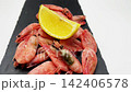 Close-up side view of a handful of pink frozen shrimp lying with a slice of lemon on a blackboard, smooth zoom. Seafood concept, seafood cooking. High quality 4k footage 142406578