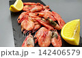 Side view close-up on a blackboard are pink frozen shrimp with lemon slices on the sides, smooth approach. Seafood concept, seafood cooking. High quality 4k footage 142406579