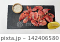 Close-up view from above, pink frozen shrimps with a slice of lemon and spices are lying on a blackboard next to each other, smoothly approaching. Seafood concept, seafood cooking. High quality 4k 142406580