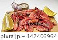 Side view on a wooden board there are pink shrimps, around which are lemon slices, garlic and spices on a white background, smooth approach. Seafood concept, cooking. High quality 4k footage 142406964