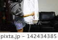 ironing a white shirt with a clothes steamer 142434385