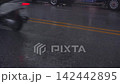 4K video focusing on a rain wet asphalt road with cars driving past during a rainy day. Shows the underside of a passenger car specifically the wheels parked on the side of the road. 142442895