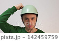 Funny man in a helmet punching himself on the head 142459759