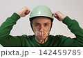 Young man putting on a protective bicycle helmet 142459785
