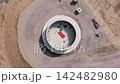 Aerial view shows circular wind turbine foundation under construction at renewable energy site. Concrete base, anchor bolts and machinery reveal engineering work for future turbine installation 142482980
