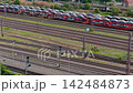 Video shows freight train loaded with new cars moving through railway yard beside multiple tracks and signals. Vehicle logistics, rail transport and automotive distribution dominate industrial scene 142484873