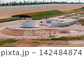 Aerial video shows wind turbine construction across farmland, with tower sections, foundations and cranes on active site. Renewable energy development expands among fields and operating turbines 142484874