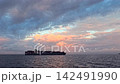 A large container ship sailing across the ocean, with clouds of the rising sun spreading across it; commercially usable live-action video footage. A large container ship sailing across the ocean, with clouds of the rising sun spreading across it; commercially usable live-action video footage. 142491990