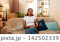 African American young woman on home sofa feels calm after resolving unknown bank transaction issue 142502339