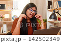 Indian woman on home table works in customer support with headset while explaining client solution 142502349