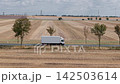 Aerial view white delivery truck travels along rural road through harvested farmland with wind turbines and power lines. Drone shows transport agriculture renewable energy infrastructure countryside 142503614