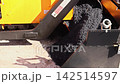Construction paving machine is parked next to building site, tools are on dashboard 142514597