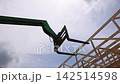 Crane lifts wooden beams into place at construction site framework for residential construction 142514598