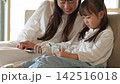 スマートフォンを使う女の子とお母さん 142516018