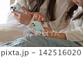 スマートフォンを使う女の子とお母さん 142516020