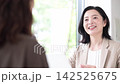 A middle-aged woman smiling and consulting with a client face-to-face; a businesswoman giving explanations and proposals in the office; communication. 142525675