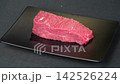 Fresh raw beef tenderloin steak slice tilted on black rectangular plate, premium red meat culinary ingredient for gourmet cooking 142526224