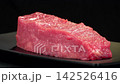 Closeup perspective shot of fresh raw beef tenderloin steak rotating on black plate, juicy red meat culinary cooking ingredient 142526416