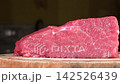 Closeup dolly shot gliding past fresh raw beef tenderloin cut on rustic wooden cutting board, organic red meat cooking ingredient 142526439