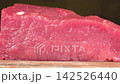 Macro dolly shot moving across fresh raw beef tenderloin steak resting on wooden cutting board, organic red meat cooking ingredient 142526440