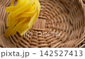 Falling organic Fettuccine pasta nest into a rustic eco-friendly rattan wicker bowl close up 142527413