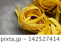 Raw italian fettuccine pasta from organic wheat in grey ceramic bowl close up. Nutritious uncooked ingredient. Rotation 142527414