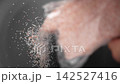 Hand sprinkles pink Himalayan salt from plastic pack, showcasing its vibrant color and texture with unique flavors and health benefits. Slow motion 142527416