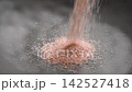 Pink Himalayan salt crystals falling into a gray kitchen bowl in slow motion close-up. Healthy organic flavor ingredients 142527418