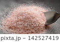 Beautiful pink granules of Himalayan salt with natural mineral content and rich flavor in metal spoon close up 142527419