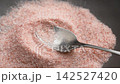 Organic pink Himalayan salt crystals falling into a metal spoon in slow motion. Healthy diet ingredient. Top view 142527420