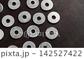 Industrial fastener washers stacked on a wooden surface. Metallic hardware spare parts. Rotation 142527422