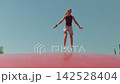 A girl does the splits while jumping the sky in the background slow motion 142528404
