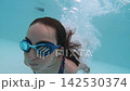 Slow motion of young girl jumping and splashing into a blue swimming pool underwater  142530374