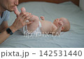 Father kissing his three month old baby son and touching his feet on bed. 142531440