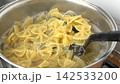 Boiling pasta in a saucepan. Whole wheat Farfalle, bow-tie or butterfly pasta Cooking in a pot with Steaming boiling water. Preparing Italian dish. Pan on stove. High angle view. Slow Motion footage 142533200