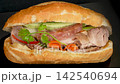 Macro zoom in shot on traditional Vietnamese banh mi pork sandwich, delicious crispy baguette with meat pate and fresh herbs 142540694