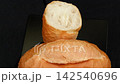 Crispy plain Vietnamese banh mi bread broken in half slowly rotating on black plate, fresh golden baguette texture 142540696