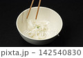 Placing fresh white rice noodles into ceramic bowl with wooden chopsticks, traditional Vietnamese pho soup cooking preparation 142540830