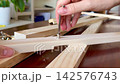 A woman's hand screws a hex screw into a wooden panel. 142576743