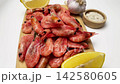 Side view on a wooden board there are pink shrimps, around which are lemon slices, garlic and spices on a white background, smooth movement along. Seafood concept, cooking. High quality 4k footage 142580605