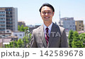 A businessman walking with the cityscape as a backdrop. 142589678
