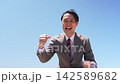 A man in a suit strikes a triumphant pose against a blue sky. 142589682