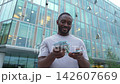 African American man holding money dollar bills on urban street in city. Businessman guy counting paper currency money outdoors near office bank building. Man holding cash. Finance economy banking 142607669
