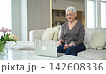 Happy middle aged senior woman siting with laptop talking on video call with friends family. Laughing mature old senior grandmother having fun talking speaking with grown up children online 142608336