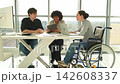Teamwork brainstorm. Diverse multiracial colleagues woman in chair for people with disability working together. Group of people sitting in creative office discussing business. Young professional team 142608337