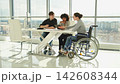 Teamwork brainstorm. Diverse multiracial colleagues woman in chair for people with disability working together. Group of people sitting in creative office discussing business. Young professional team 142608344