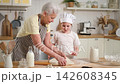 Happy family in kitchen. Grandmother and granddaughter child cook in kitchen together. Grandma teaching kid girl roll out dough bake cookies. Household teamwork helping family generations concept 142608345
