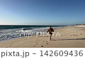Woman walking with her dog along the sandy shore 142609436